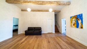 A spacious living room with wooden flooring, a black sofa, and a painting on the wall. - Palazzo Salviati Quaratesi (Florence)