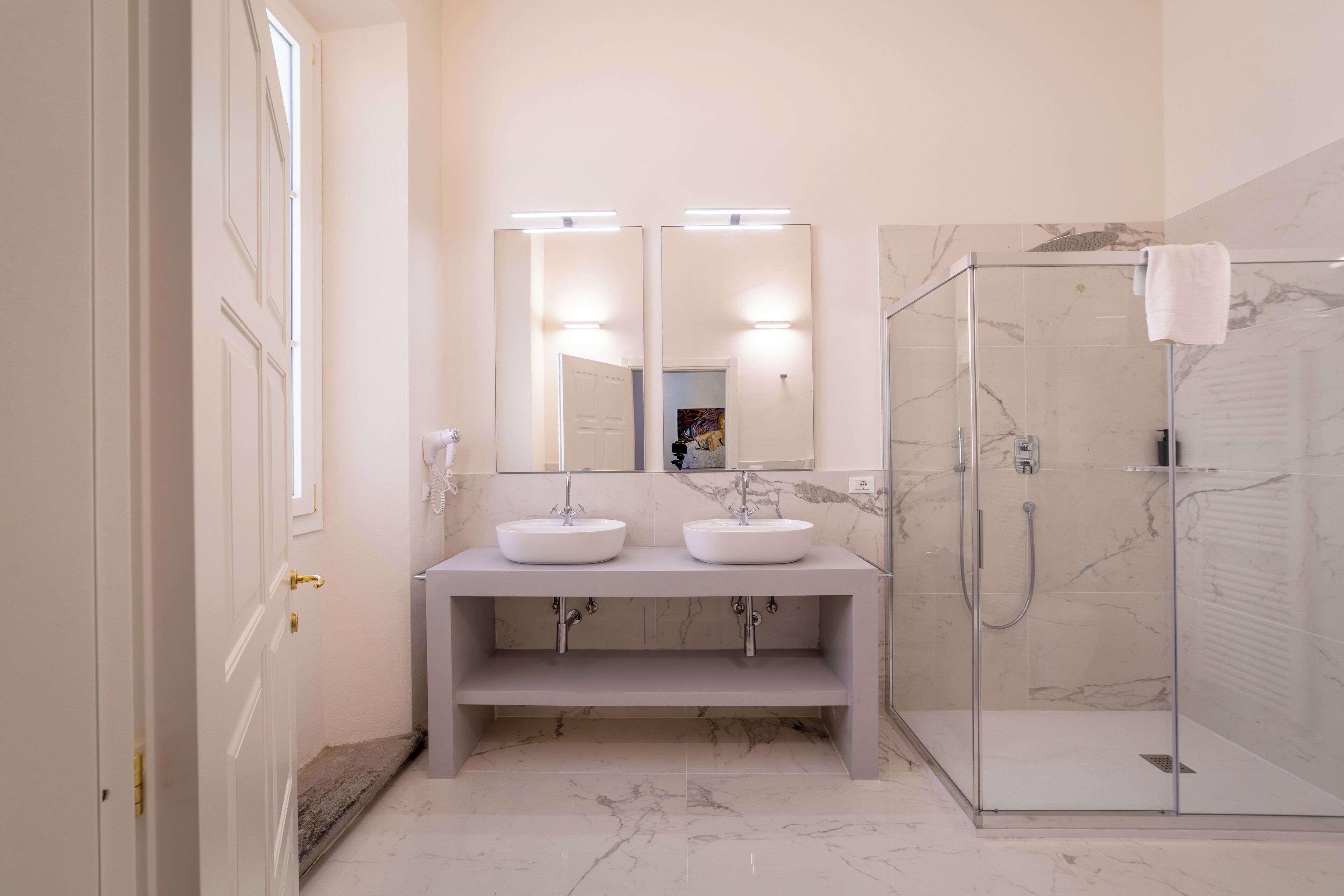 Une salle de bain avec deux lavabos, un grand miroir et une douche à parois de verre.