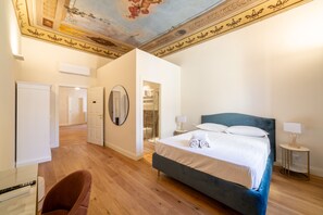 Une chambre à coucher avec un grand lit, un miroir, une chaise et un plafond orné d’éléments décoratifs.