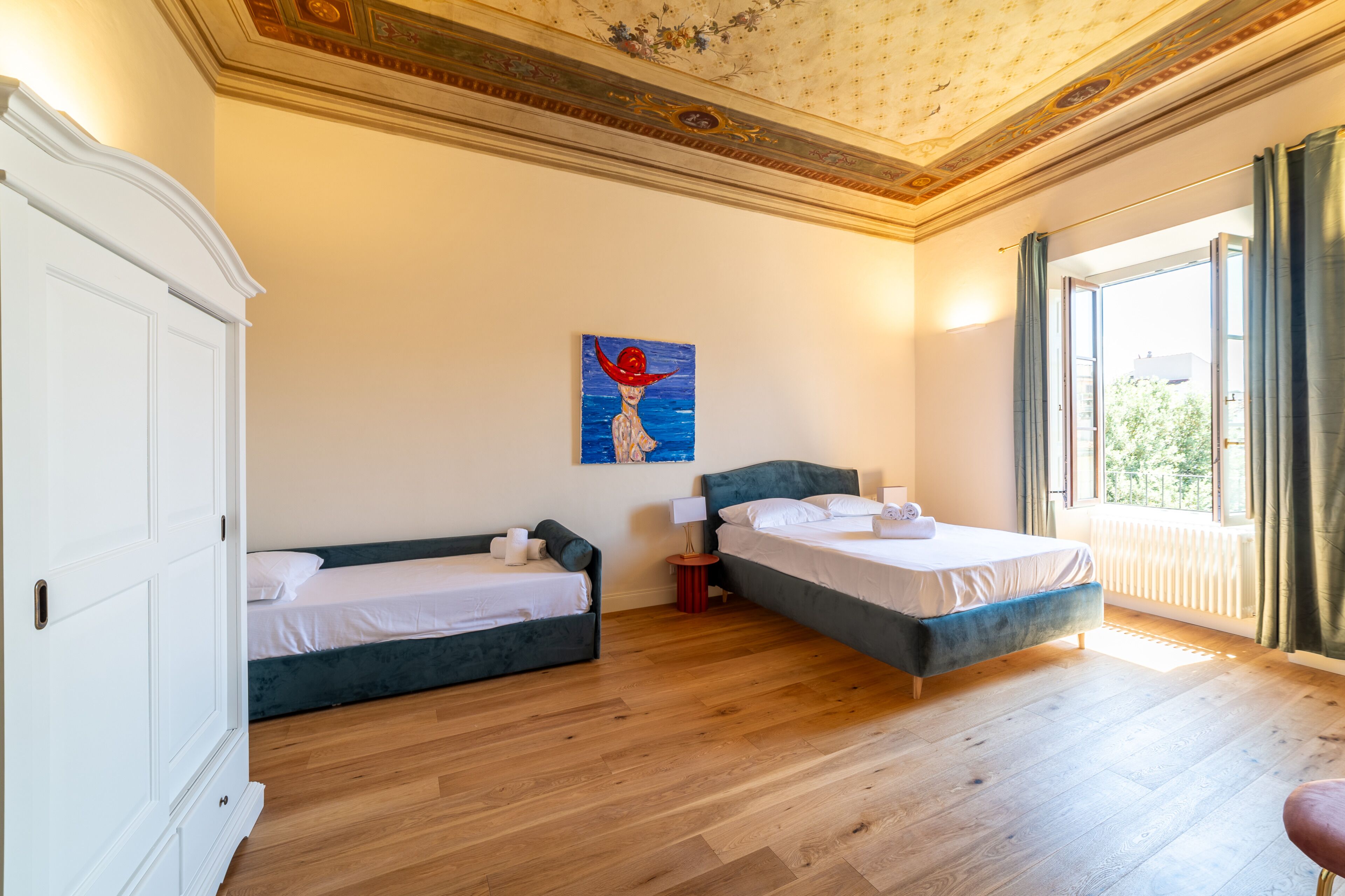 Una habitación con dos camas, un armario y un cuadro en la pared.