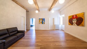 A spacious room with a wooden floor, a black sofa, and two paintings on the walls. - Palazzo Salviati Quaratesi (Florence)
