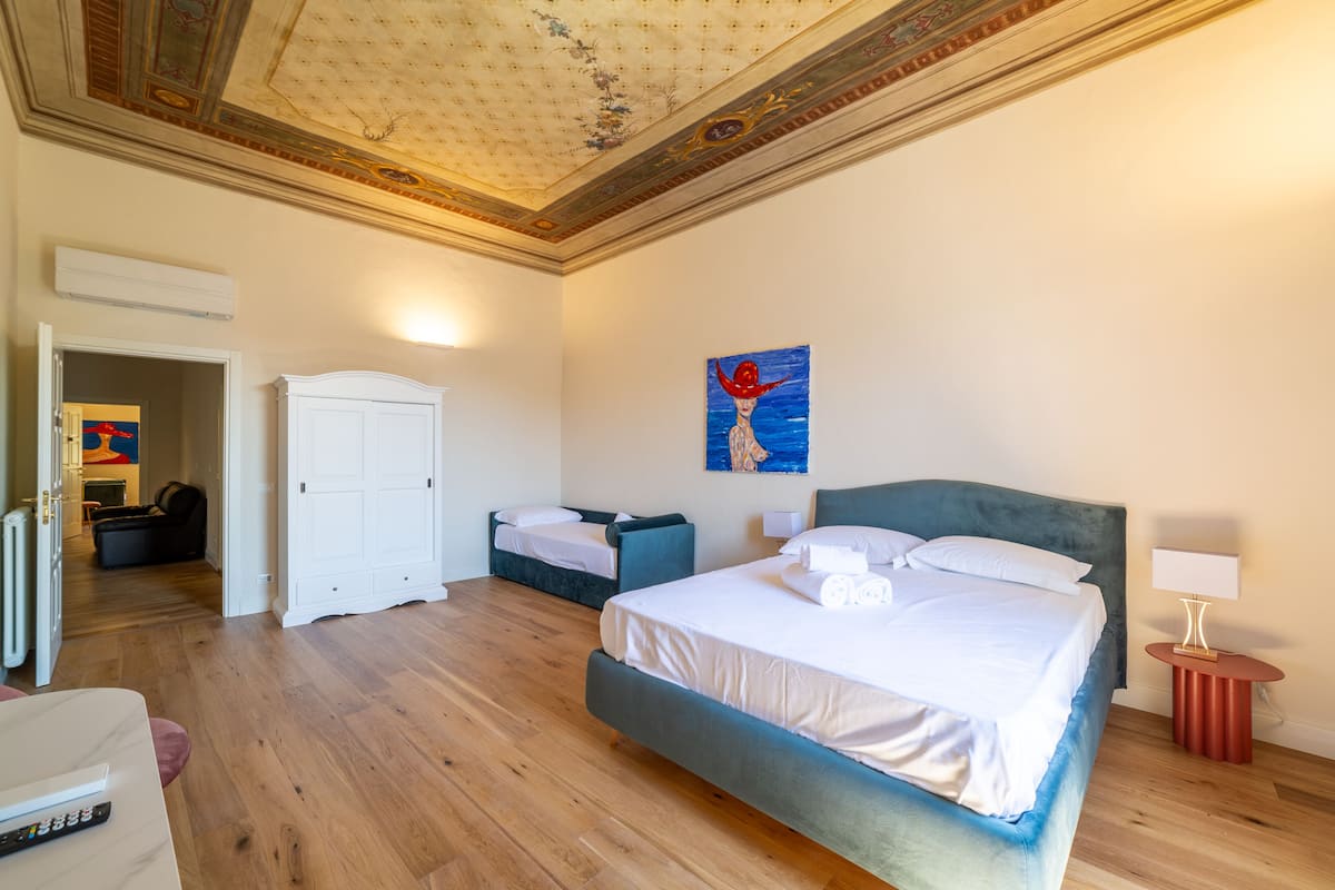 Une chambre d’hôtel avec un grand lit, une armoire, un bureau avec une chaise et un tableau au mur.