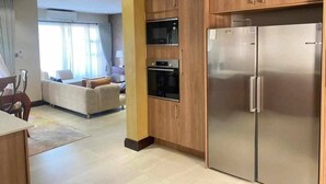 A modern kitchen with wooden cabinets, a stainless steel refrigerator, and built-in appliances. - Roma Park 2 Bedroom Villa (Lusaka)