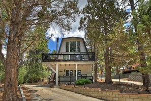 A two-story building with a balcony, surrounded by trees.