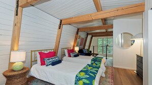 Un dormitorio con dos camas, vigas de madera, un espejo y vistas al exterior.