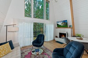 Una sala de estar moderna con chimenea, un ventanal grande y un comedor.