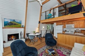 A spacious living area with a fireplace, a television, and a dining table with chairs.