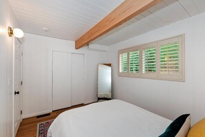 A bedroom with a bed, a wardrobe, a mirror, and a window with blinds. - Summit View Treehouse By Destination Big Bear: Pet Friendly! Close to Bear Mtn! Walking Distance to Alpine Zoo! (Big Bear Lake)