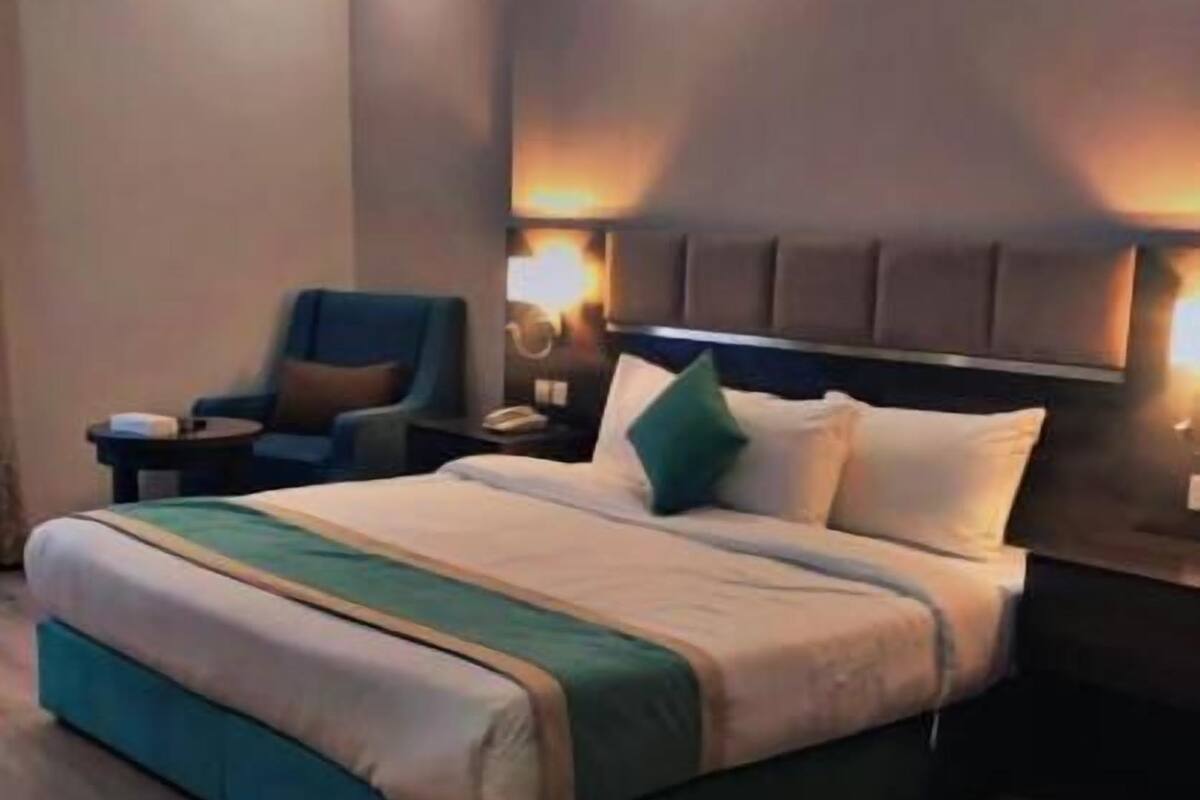 A modern hotel room with a large bed, a chair, and a nightstand.