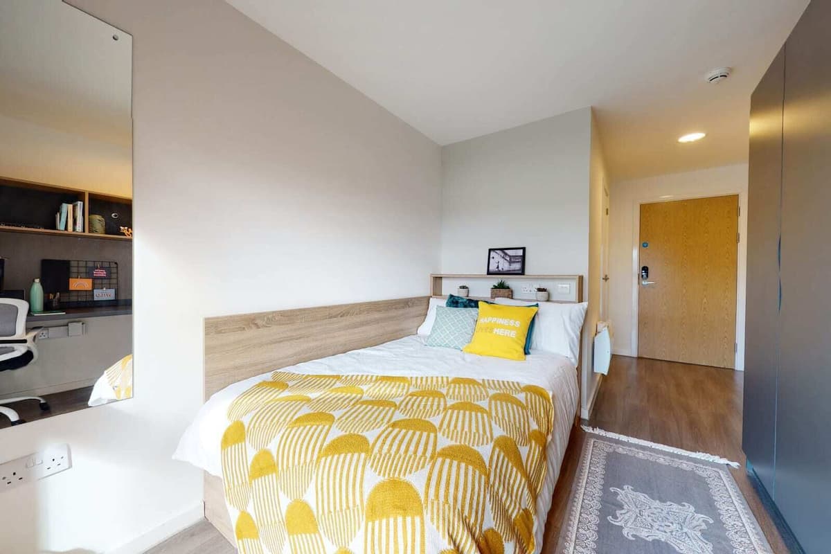 A hotel room with a bed, a desk, and a chair.
