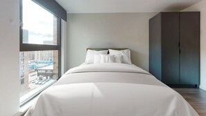Ein modernes Schlafzimmer mit großem Fenster, einem Bett und einem Kleiderschrank.