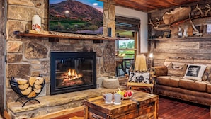 A stone fireplace with a TV above it, a cozy seating area with a couch and a coffee table, and a wooden ceiling. - Private Pond, Weddings for up to 100! Pool is open (Sevierville)