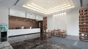 A modern hotel lobby with a marble reception desk, a chandelier, a seating area, and a bookshelf. - ShanShui S Hotel (Guangzhou)