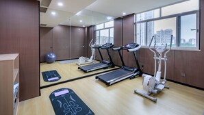 A modern gym with treadmills, an elliptical, and a rowing machine, large windows, and a mirror. - ShanShui S Hotel (Guangzhou)