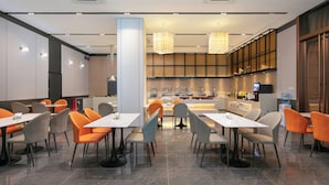 A modern dining area with tables and chairs, a counter with a display, and a large pillar. - ShanShui S Hotel (Guangzhou)