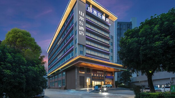 Un moderno edificio de hotel con varios pisos, ventanas amplias y una entrada destacada.
