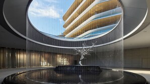 A modern building with a circular atrium, a central water feature, and a reflective pool. - Xianghu Liberty Manor (Hangzhou)