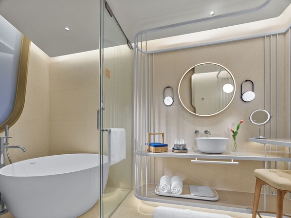 Een moderne badkamer met een vrijstaand ligbad, een douchecabine met glazen wanden en een wastafel met een wastafel en spiegel.