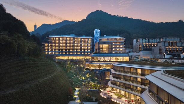 A modern hotel complex with multiple buildings, a central tower, and surrounding landscaped gardens. - Xianghu Liberty Manor (Hangzhou)