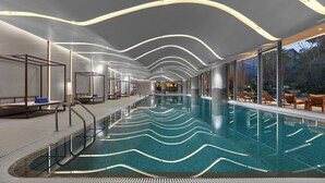 A modern indoor swimming pool with a wavy light design on the ceiling and clear glass walls offering views of the outdoors. - Xianghu Liberty Manor (Hangzhou)