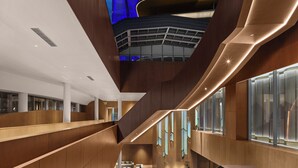 A modern interior with a central staircase, a high ceiling, and a view of a building with a blue-lit facade. - Xianghu Liberty Manor (Hangzhou)
