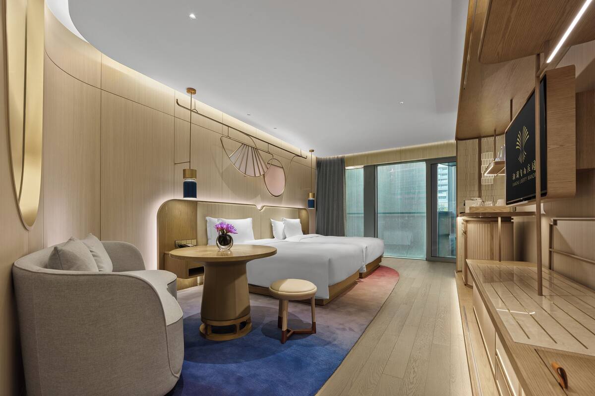 Una habitación de hotel moderna con cama, escritorio, silla y vistas a la ciudad.