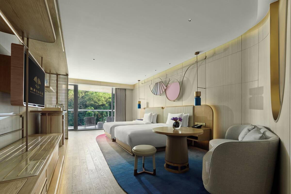 Una habitación de hotel moderna con una cama grande, un escritorio, una silla y un televisor.