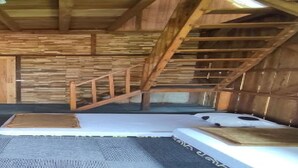 A rustic wooden room with a sloped ceiling, a staircase, and a checkered floor. - EXPRESS O 91041 Cottage Saung Suluh (Baturaden)
