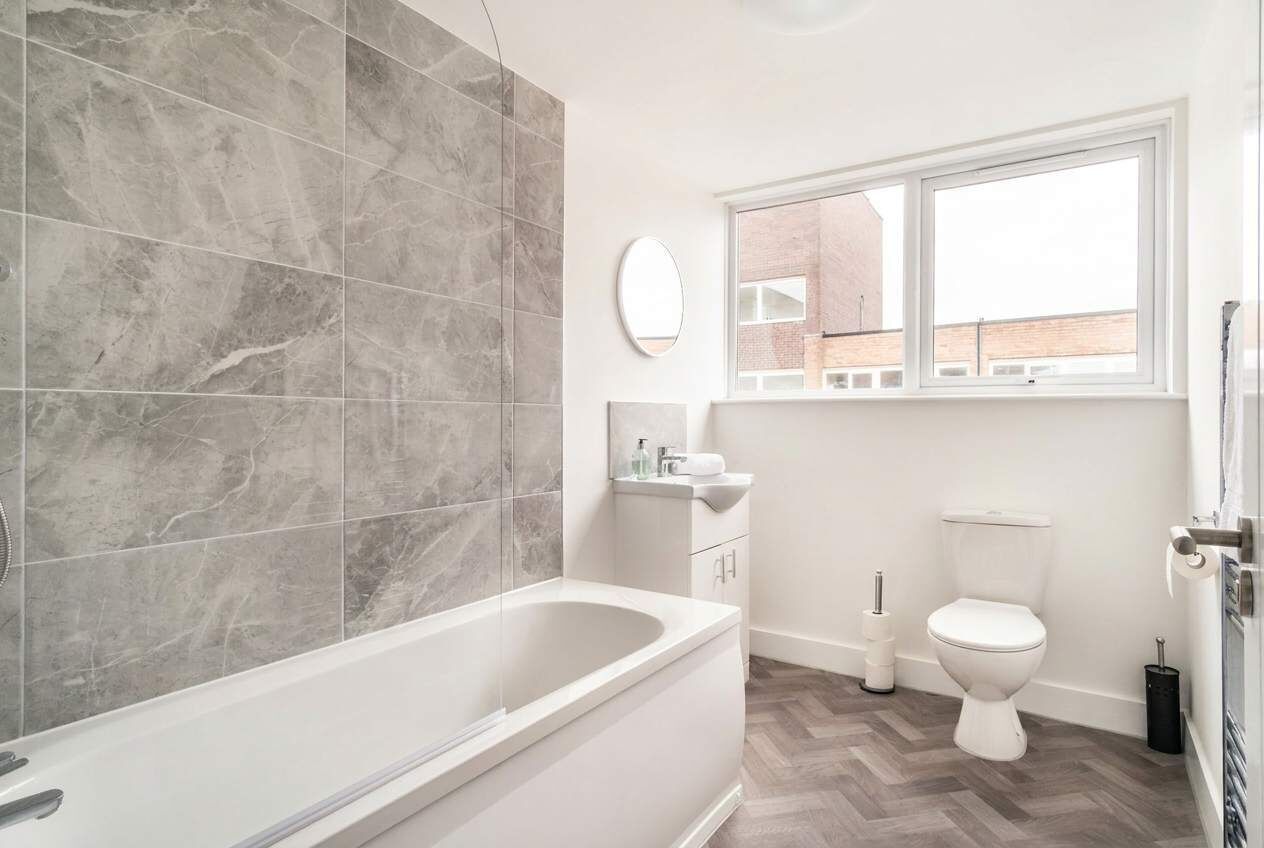 A modern bathroom with a freestanding bathtub, a toilet, a sink, and a window.