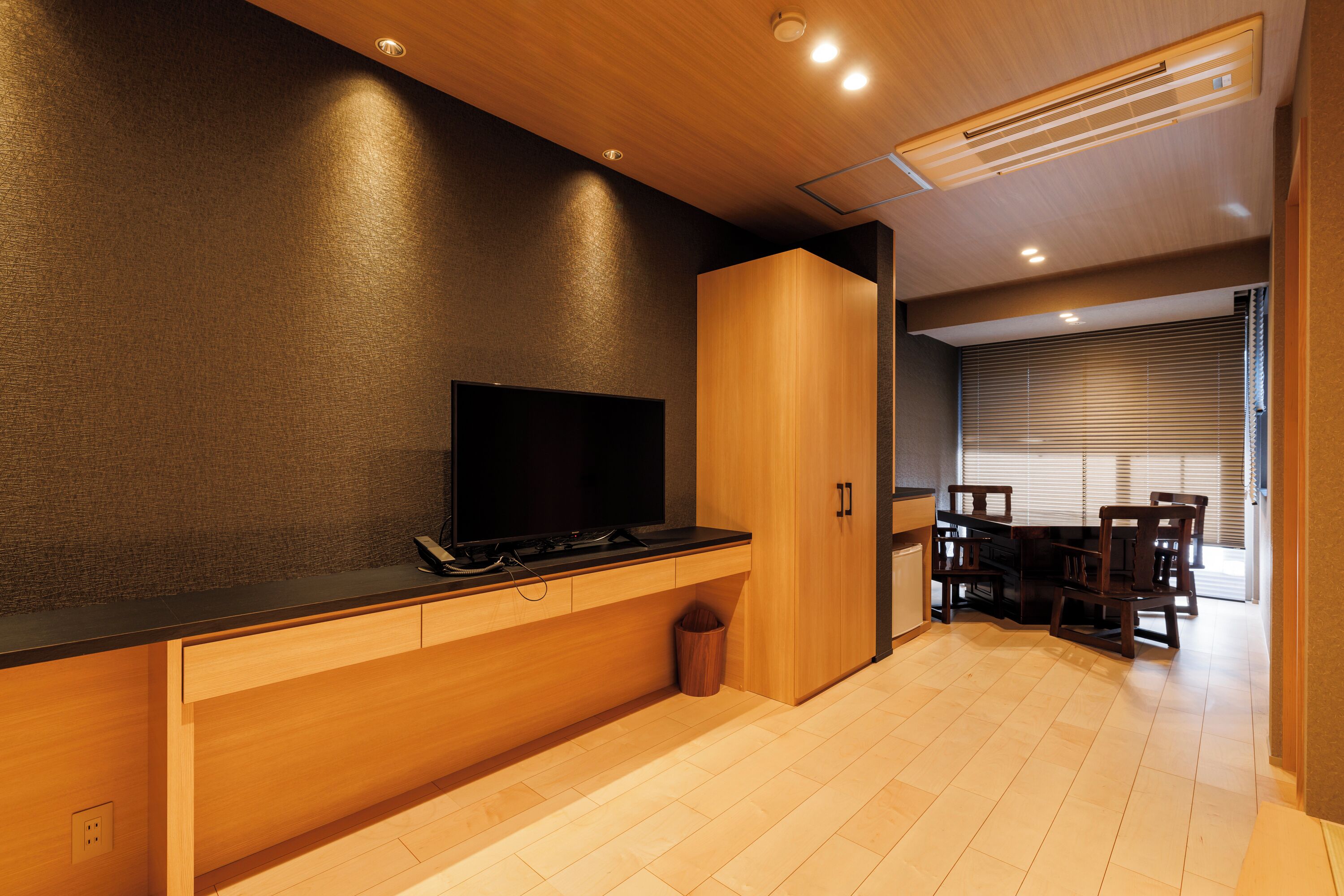 A modern kitchen with a flat-screen TV, wooden cabinets, and a dining area with a table and chairs.
