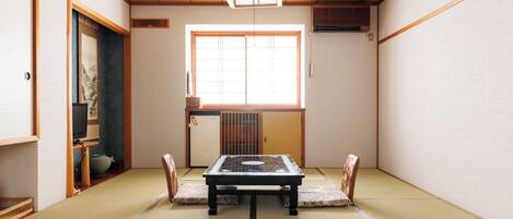 A traditional Japanese room with tatami flooring, a low table, and sliding doors.