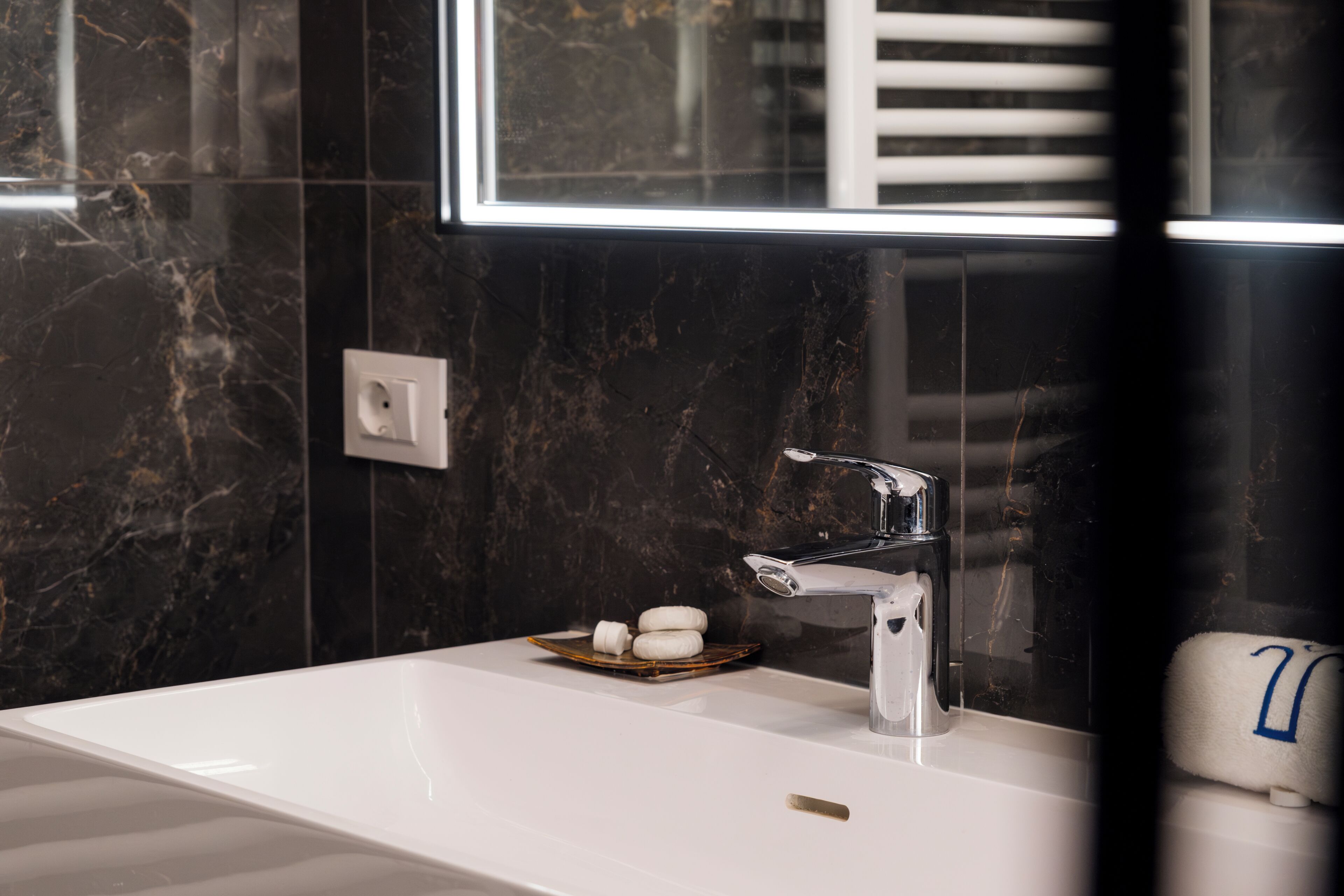 A modern bathroom with a white sink, a mirror, and a towel rack.