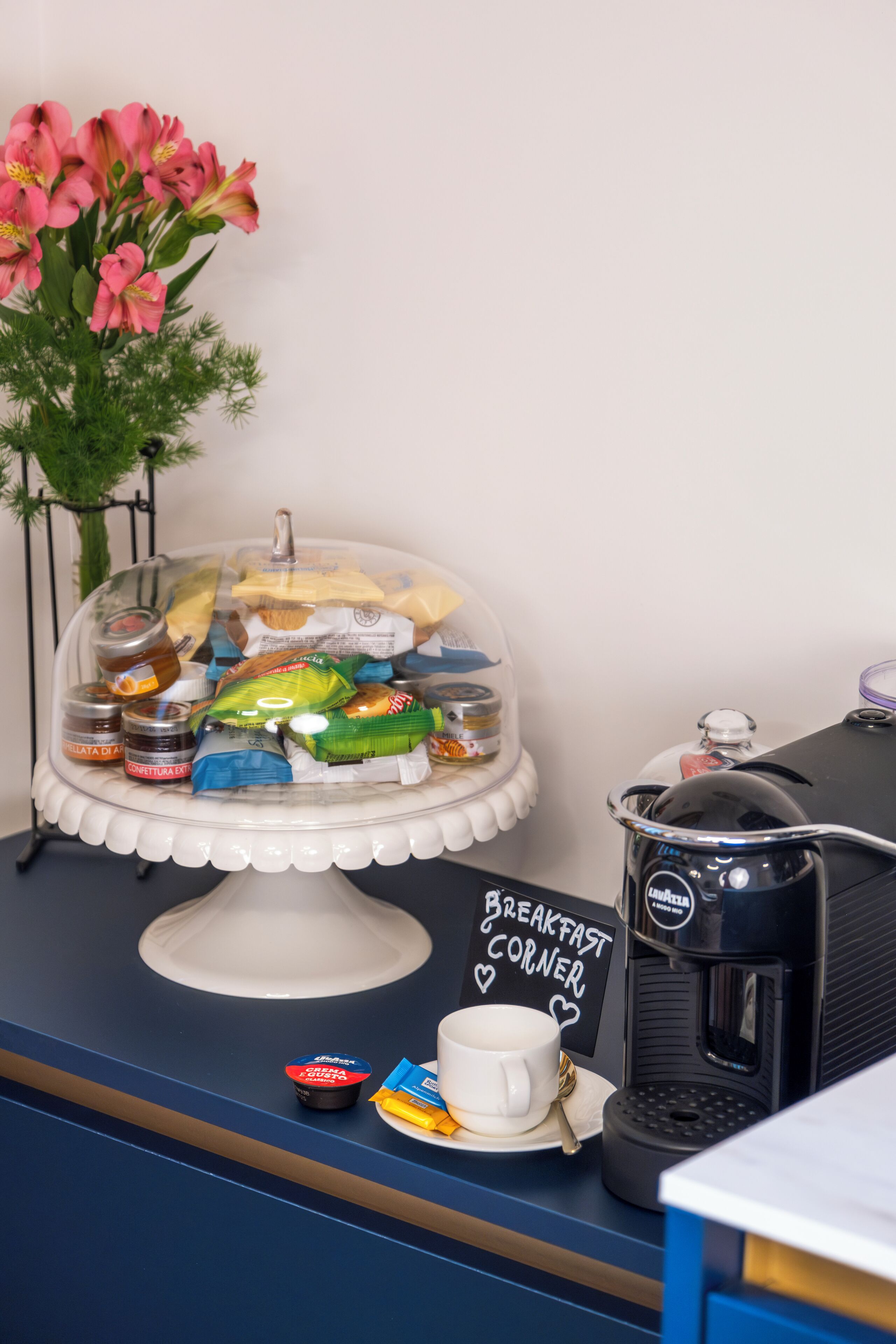 A breakfast station with a variety of pastries, a coffee machine, and a sign that reads "Breakfast Corner."