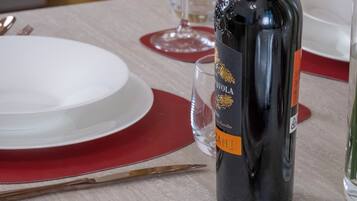 A table set for a meal with a bottle of wine, glasses, and cutlery.