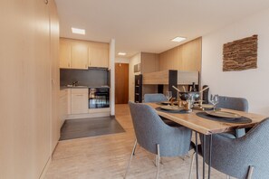 A modern kitchen with wooden cabinets and a dining area with a table set for two.