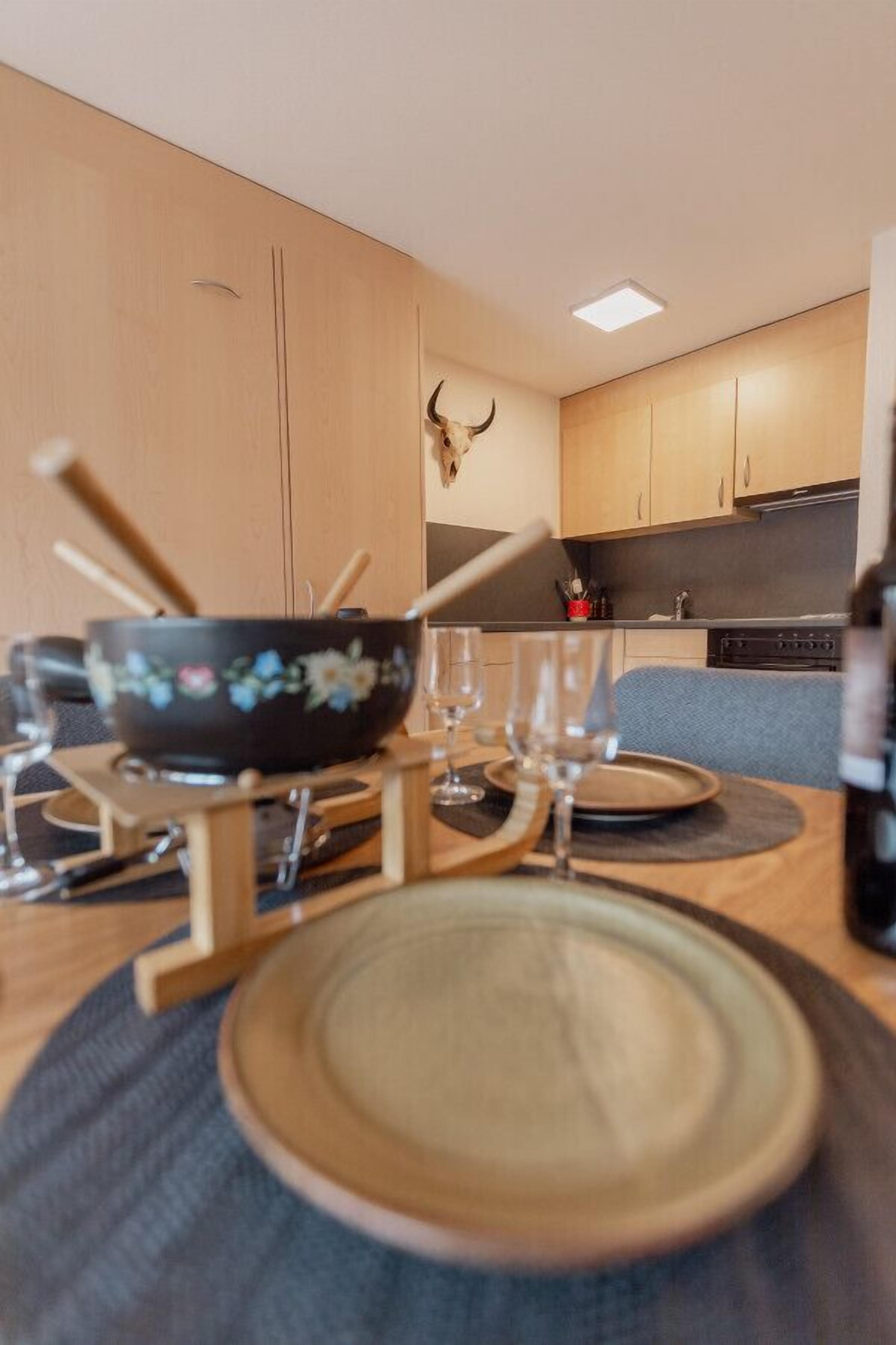 A dining area with a table set for two, featuring a bowl and glasses.
