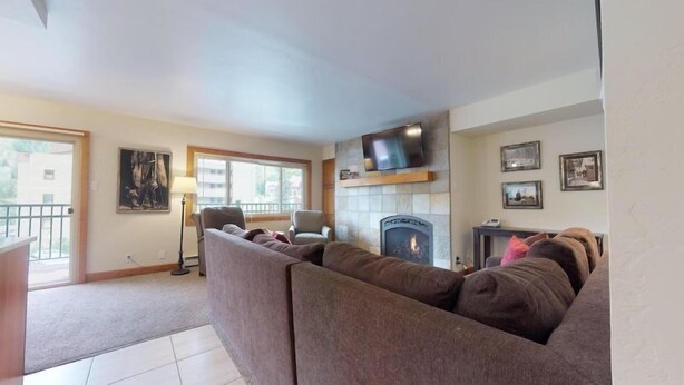 A living room with a sofa, a fireplace, a television, and a window.