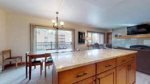 A spacious kitchen with a large island, wooden cabinets, and a built-in TV.