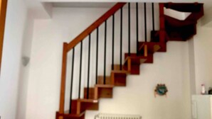 A staircase with wooden steps and black railings, a radiator, and a white cabinet.
