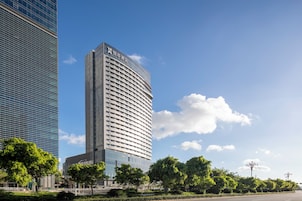 Un hotel moderno con fachada curva, ventanas amplias y cielo despejado.