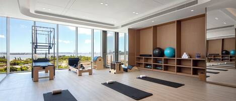 Un gimnasio moderno con amplios ventanales, equipamiento de ejercicio y vistas al exterior.