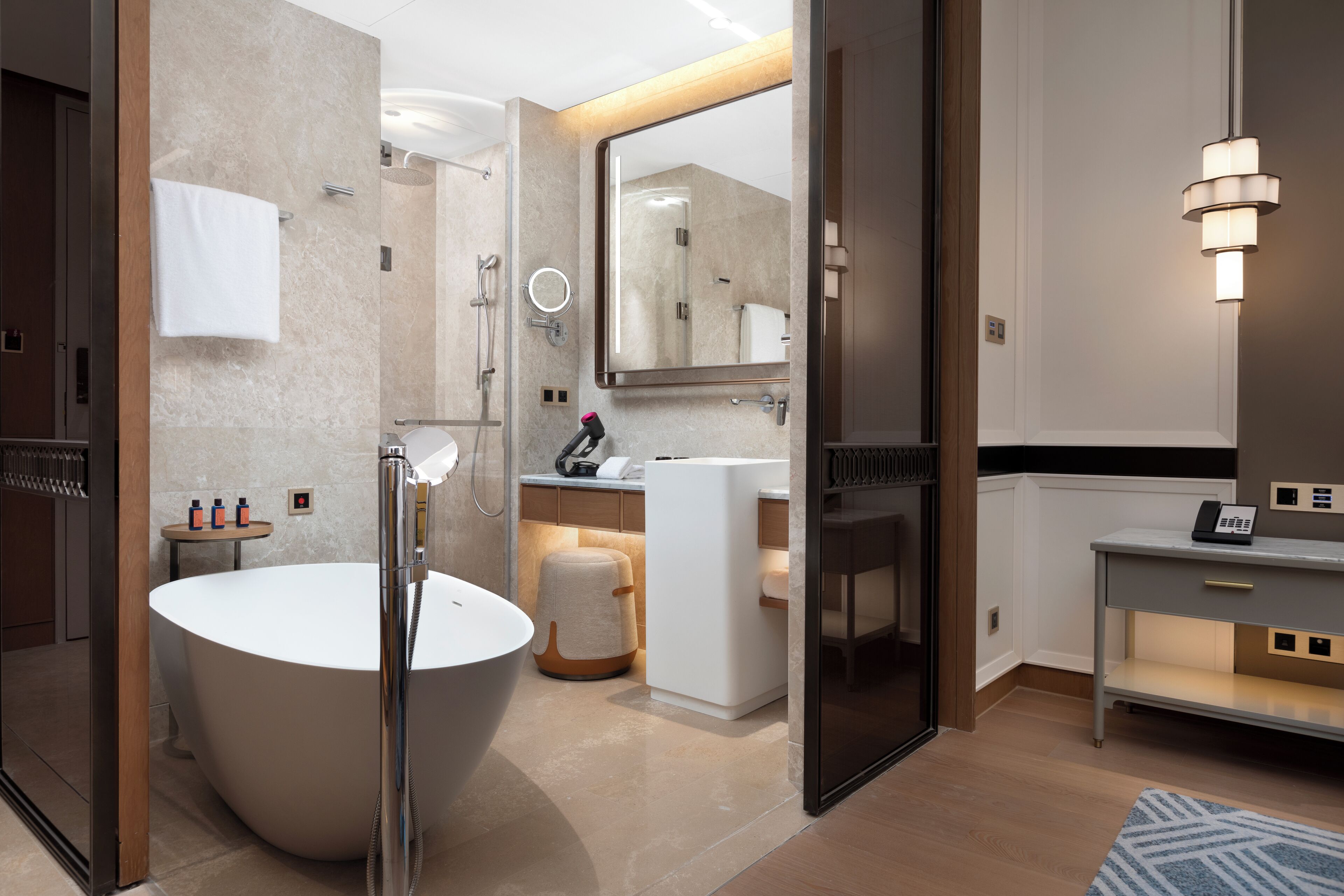 Un bagno moderno con una vasca freestanding, un mobile lavabo con specchio e un portasciugamani.