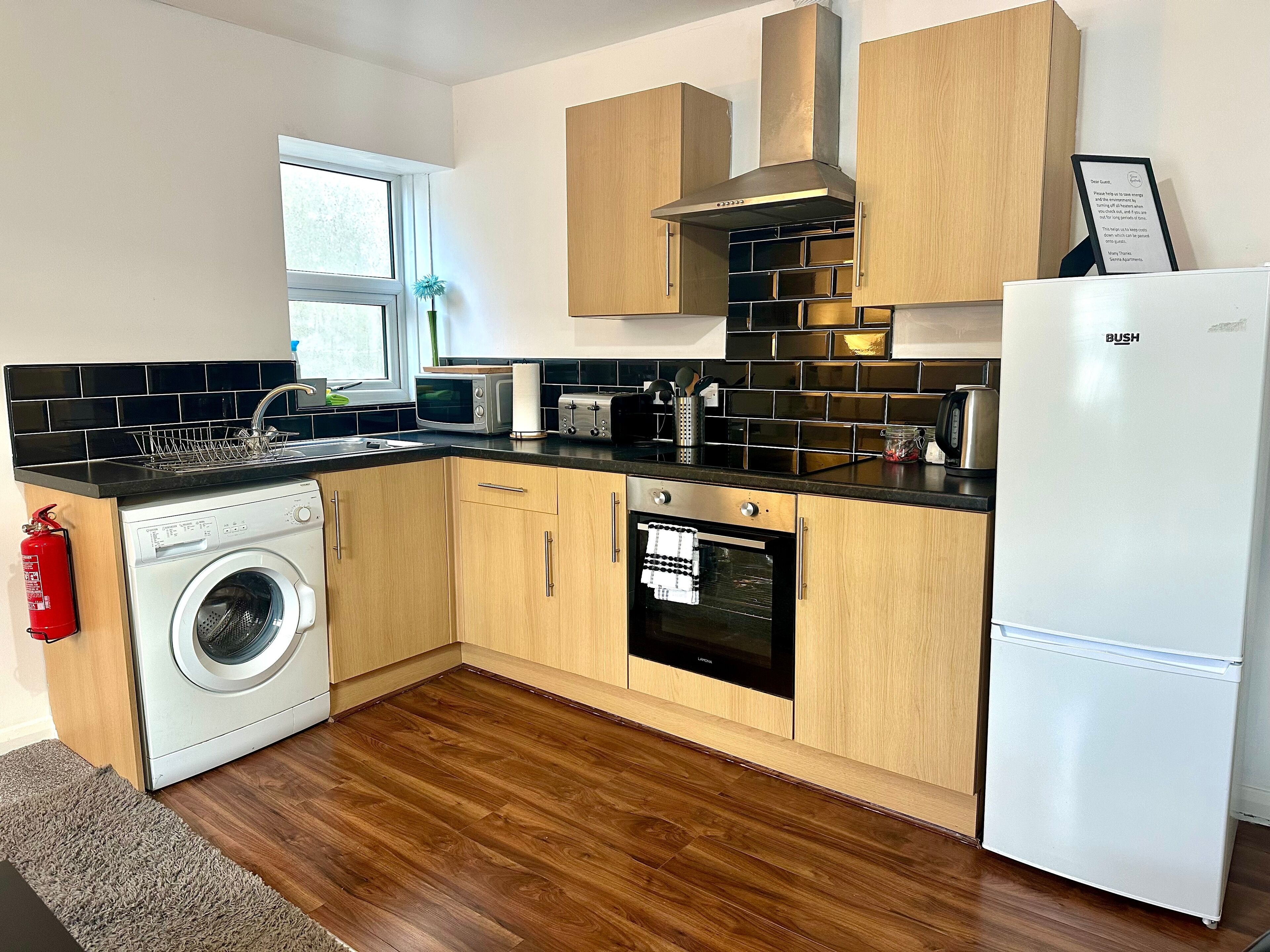 Eine kleine Küche mit Waschmaschine, Backofen und Kühlschrank.