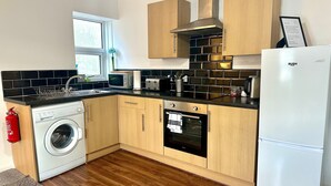 A compact kitchen with a washing machine, oven, and a refrigerator.