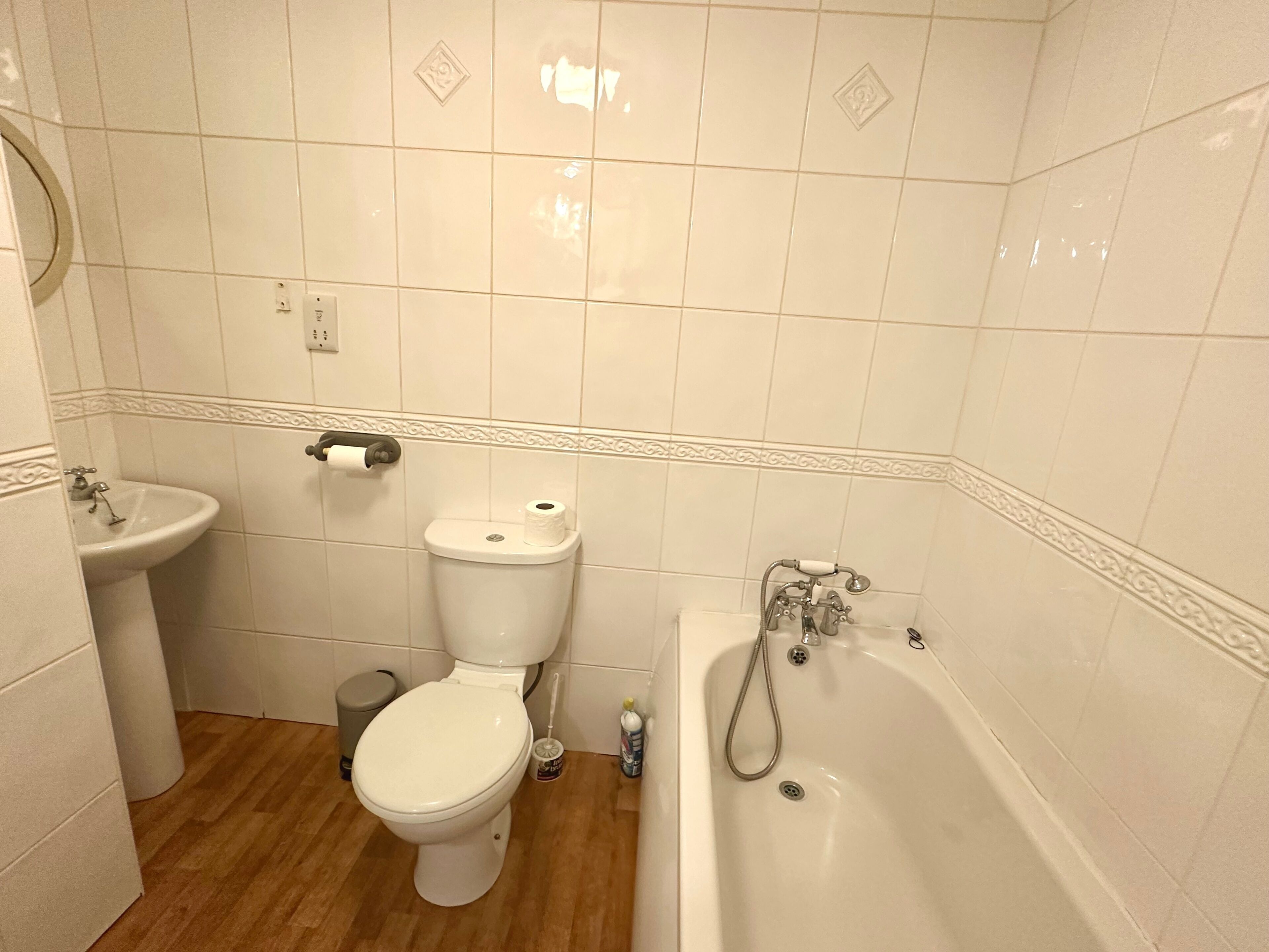 Et badeværelse med toilet, vask og badekar.