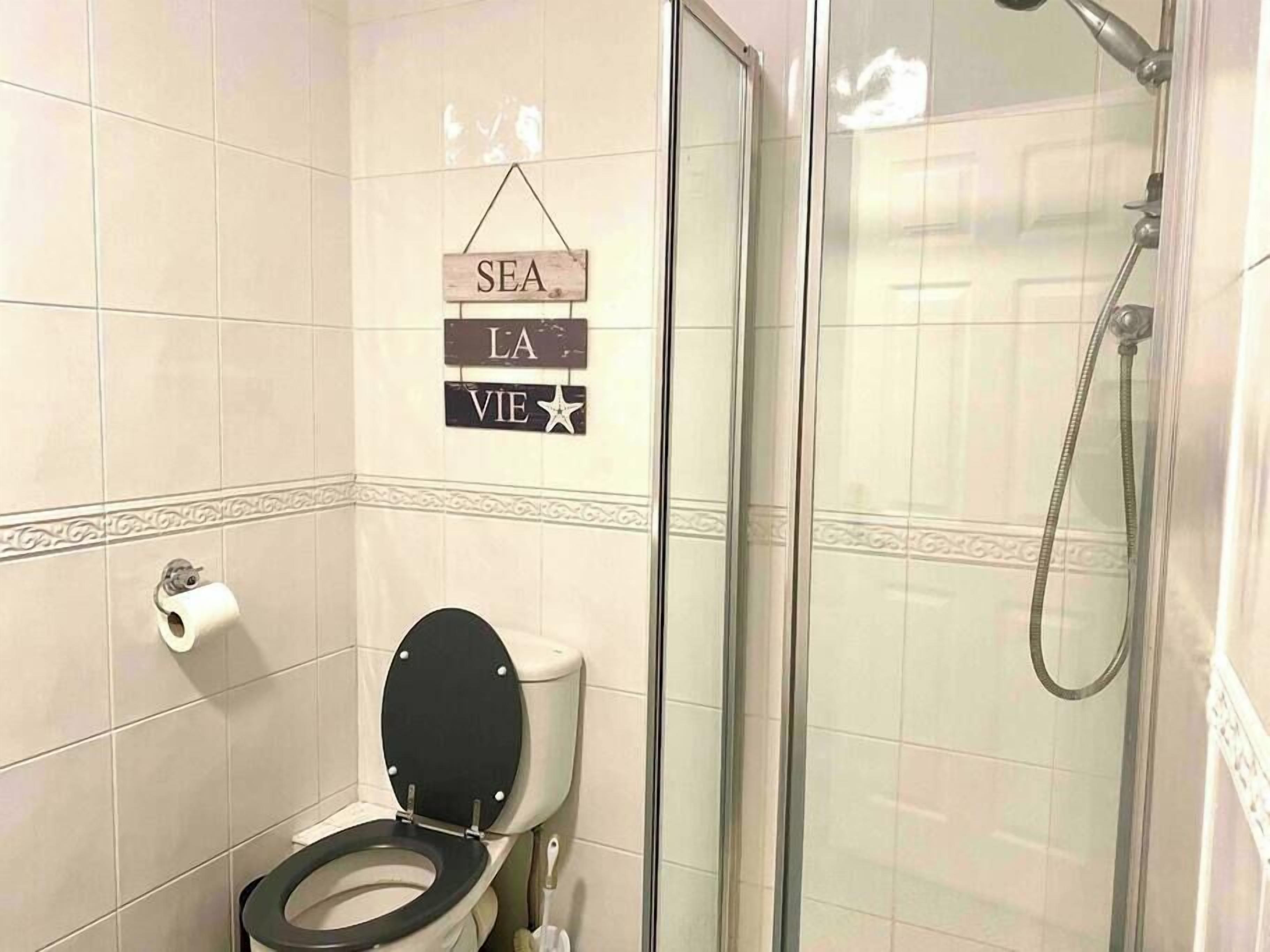 Une salle de bain avec des toilettes, une douche et une pancarte sur laquelle on peut lire : « SEA LA VIE ».