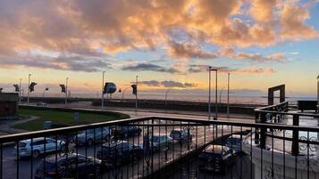 A parking lot with cars, a curved road, and a sunset view.