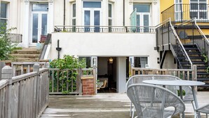 Un immeuble à plusieurs étages doté d’un balcon et d’un espace extérieur aménagé pour s’asseoir.