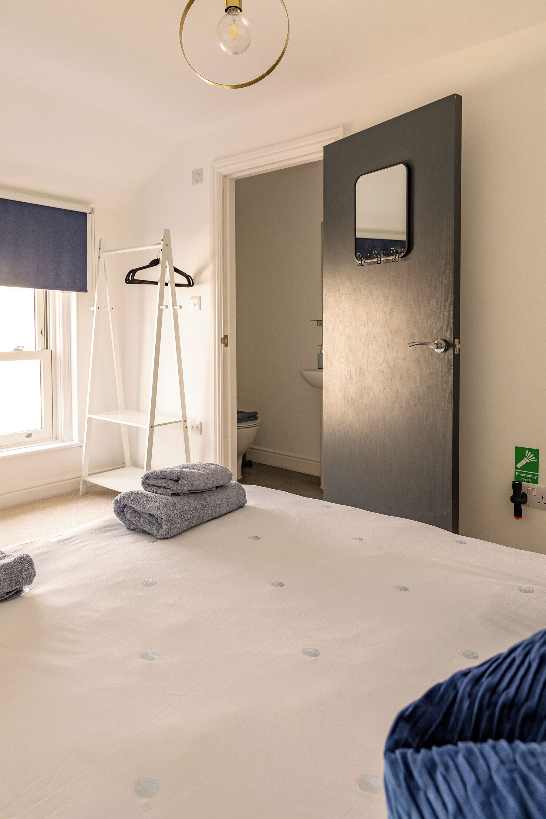 A bedroom with a bed, a ladder, a towel, a door with a mirror, and a window.