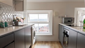 Une cuisine moderne équipée d’un lave-linge intégré, d’un four à micro-ondes et offrant une vue par une fenêtre.